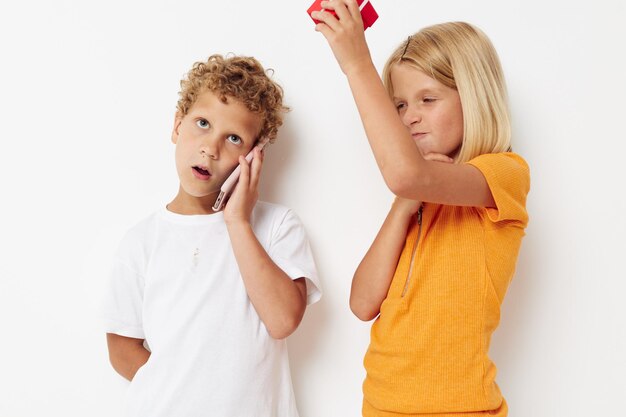 Foto niño hablando por teléfono mientras está de pie contra un fondo blanco