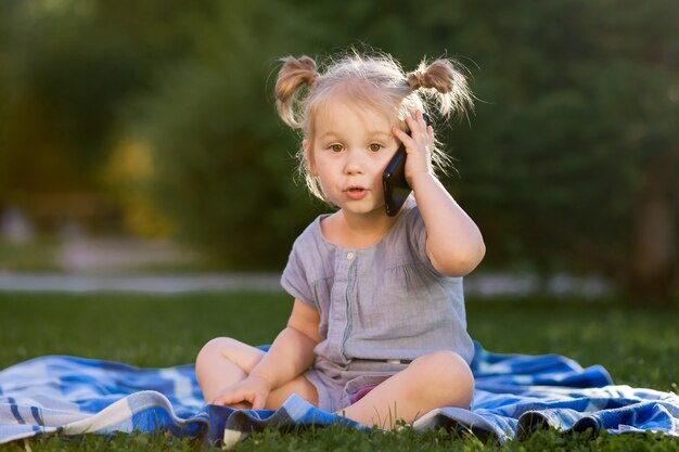 Niño hablando por un teléfono móvil en el parque