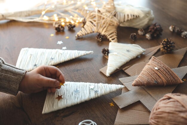 Foto niño hace decoración navideña de hilo