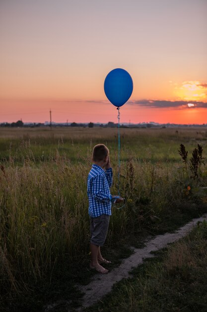 Niño hace sus sueños al aire libre con globo Correr por el campo Hermosa libertad de tarjeta de verano