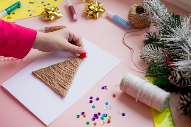 El niño hace una tarjeta de Navidad para las vacaciones de invierno. Manualidades y manualidades de bricolaje para Navidad