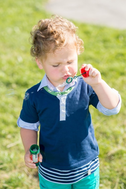 Niño haciendo burbujas en el parque en un día soleado de verano