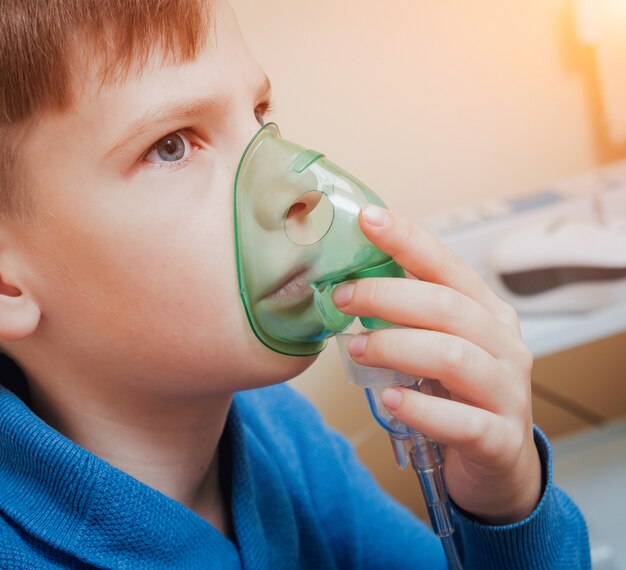 Niño haciendo inhalación con nebulizador en la clínica.