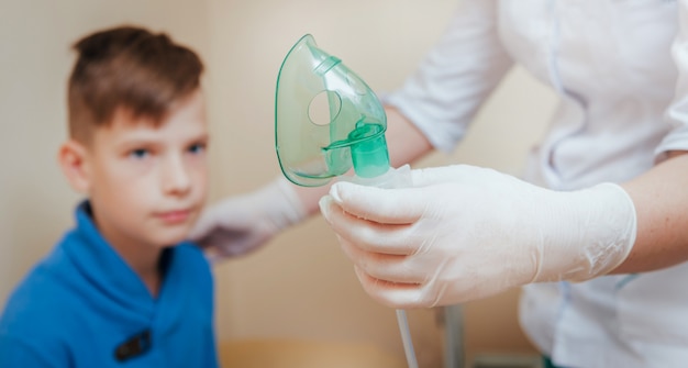 Niño haciendo inhalación con nebulizador en la clínica.