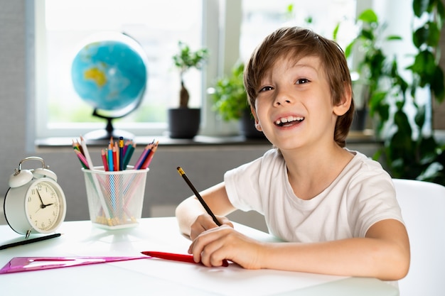 El niño haciendo lecciones en casa en la mesa educación a distancia educación en línea
