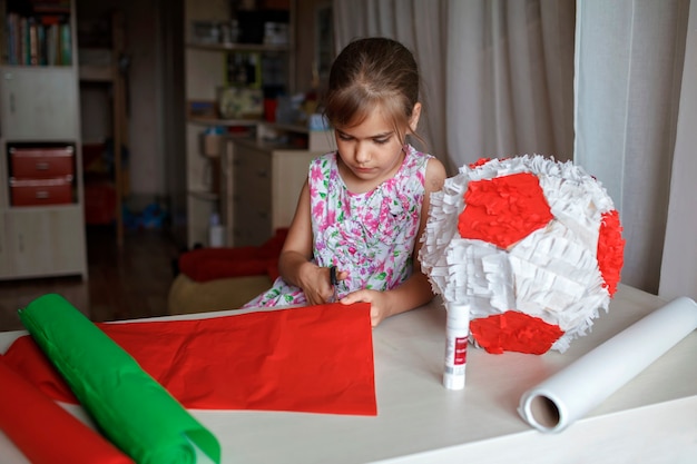 Niño haciendo piñata con cartón de caja usada y decoración de bricolaje de papel de color en la fiesta de cumpleaños