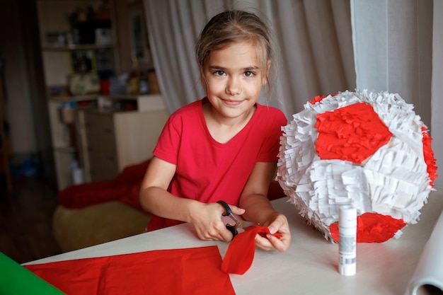 Niño haciendo piñata con cartón de caja usada y decoración de bricolaje de papel de color en la fiesta de cumpleaños