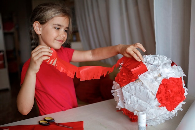 Niño haciendo piñata con cartón de caja usada y decoración de bricolaje de papel de color en la fiesta de cumpleaños