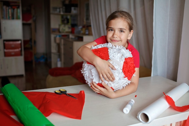 Niño haciendo piñata con cartón de caja usada y decoración de bricolaje de papel de color en la fiesta de cumpleaños