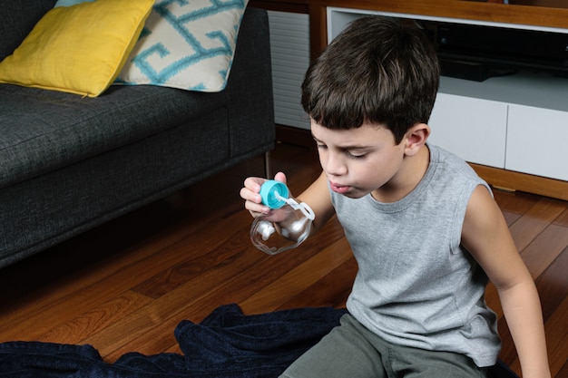 niño haciendo pompas de jabón en casa