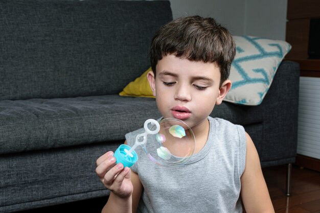 niño haciendo pompas de jabón en casa