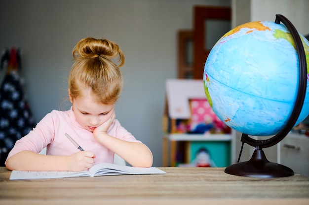 Niño haciendo la tarea, leyendo libros cerca del globo