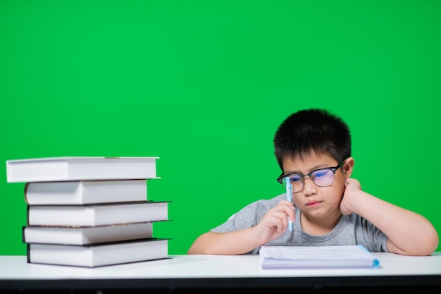 niño haciendo la tarea en pantalla verde niño escribiendo papel concepto de educación