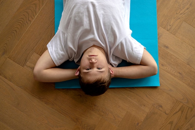 Foto niño haciendo yoga en la vista superior de la alfombra