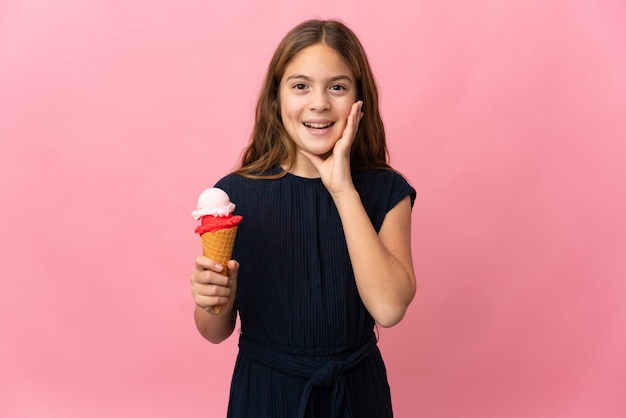 Niño con un helado de cucurucho sobre rosa aislado con sorpresa y expresión facial conmocionada