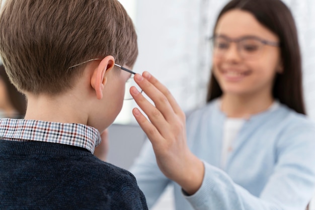 Niño y hermana en la tienda probándose gafas