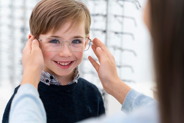 Niño y hermana en la tienda probándose gafas