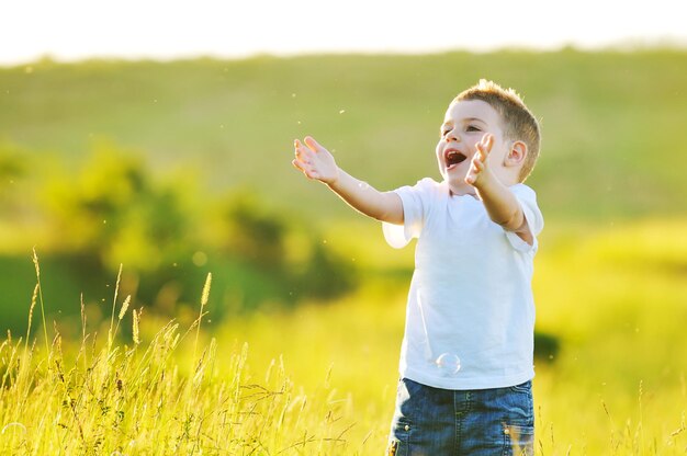 niño hermoso joven feliz diviértete en eadow con juguete de pompas de jabón