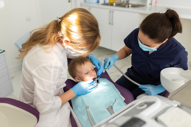 Niño hermoso niño en la silla del dentista la oficina trata los dientes