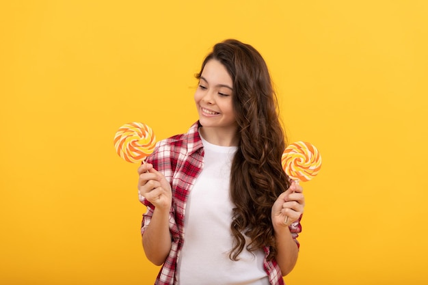 Niño hipster con cabello largo y rizado sostenga caramelos de azúcar de piruleta en la tienda de dulces de caramelo de palo