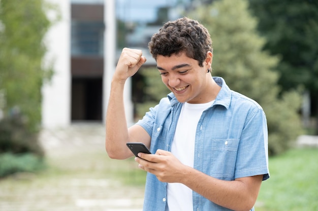 Niño hispano celebrando buenos resultados por teléfono