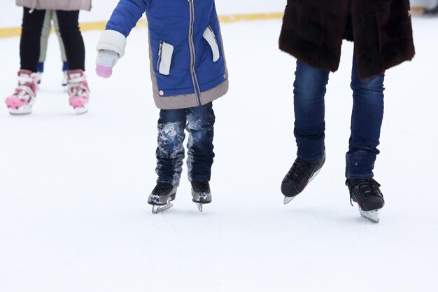 El niño y el hombre patina en la pista de hielo.