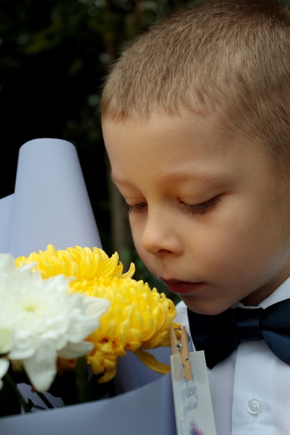 Foto un niño huele crisantemos