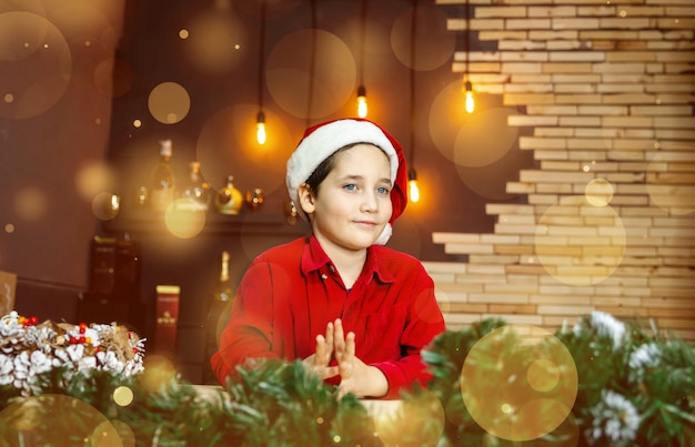 Niño increíble en gorro de santa claus sobre fondo dorado borroso