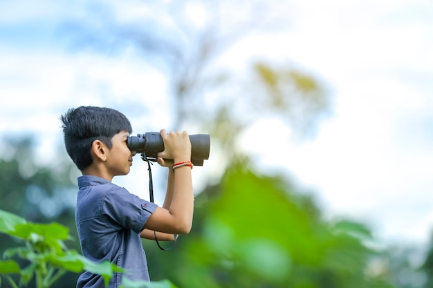 Niño indio disfruta en la naturaleza con binoculares