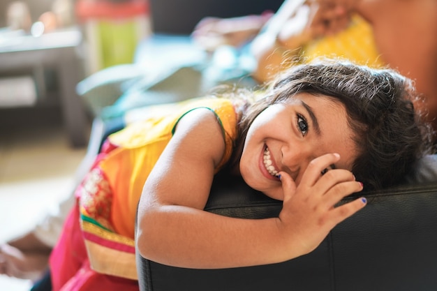 Niño indio feliz divirtiéndose sentado en el sofá con los padres en casa