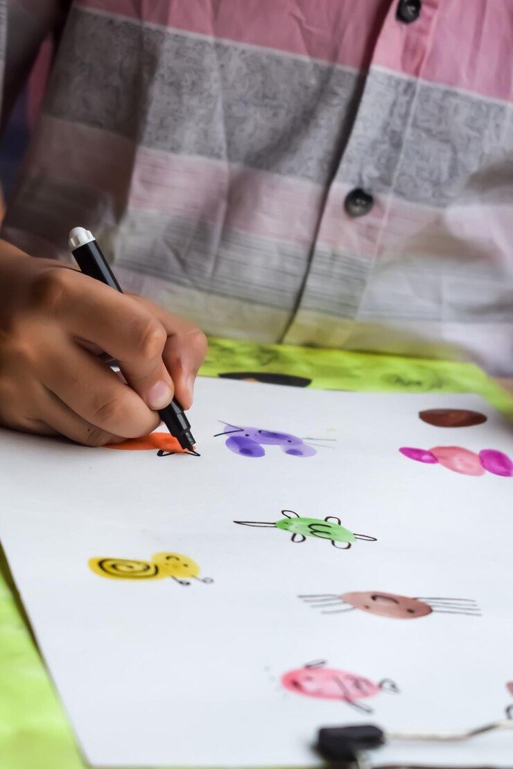 Foto niño indio inteligente realiza pintura con los pulgares con diferentes kits de acuarela coloridos durante las vacaciones de verano niño indio lindo haciendo pintura colorida con el pulgar dibujando en una mesa de madera