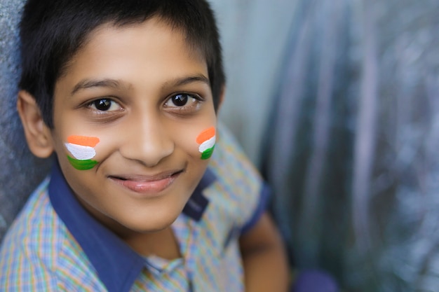 Niño indio joven con bandera india en la cara