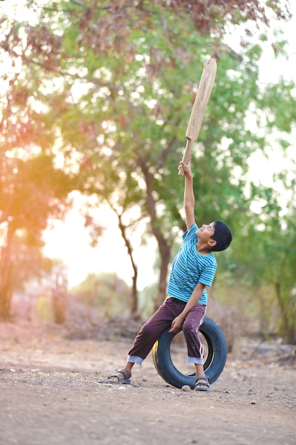 Niño indio rural jugando al cricket