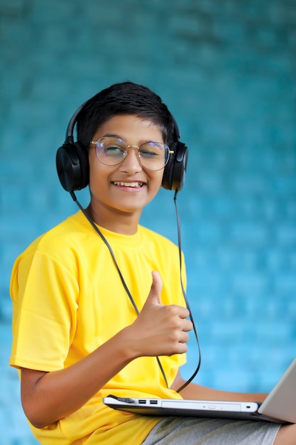 Niño indio usando auriculares y mostrando golpes