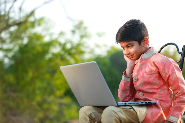 Niño indio vistiendo telas tradicionales y usando laptop