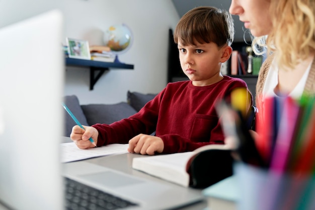 Niño insatisfecho haciendo la tarea con su madre