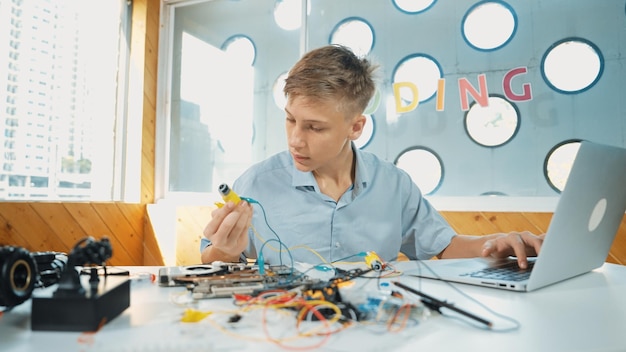 Niño inspecciona o aprende a usar herramientas electrónicas para arreglar el modelo de coche Edificación