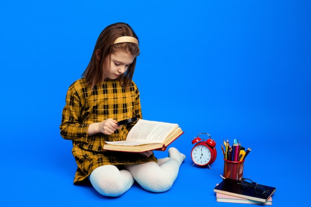 Niño inteligente con lupa para leer un libro durante los estudios