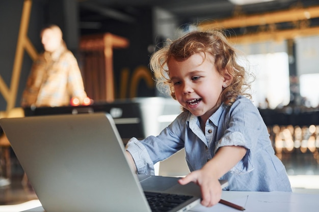 Niño inteligente con ropa informal que usa una computadora portátil con fines educativos o divertidos