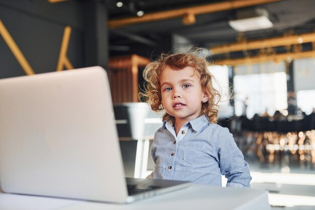 Niño inteligente con ropa informal que usa una computadora portátil con fines educativos o divertidos