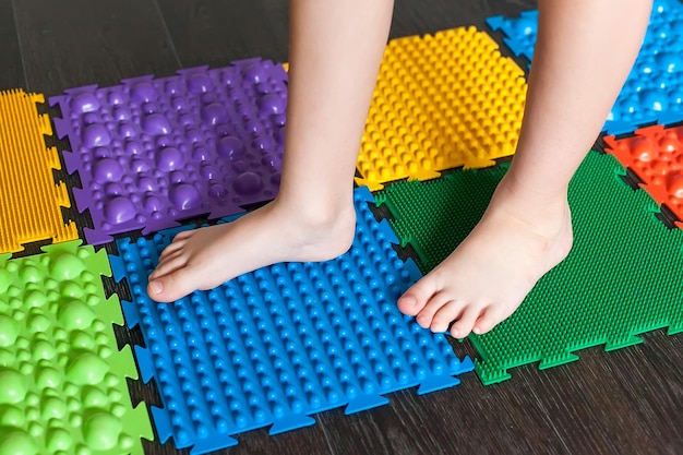 Foto el niño está involucrado en alfombras de masaje ortopédico para piernas de diferente dureza y textura masaje de las terminaciones nerviosas de las piernas prevención de pies planos en niños tratamiento de deformidad del pie