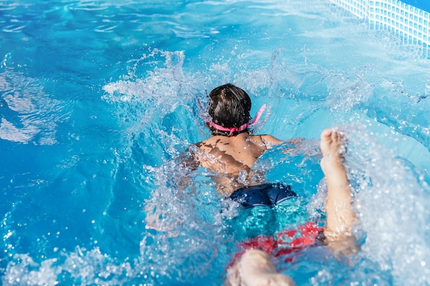 Foto niño irreconocible jugando en una pequeña piscina desmontable de una casa niño nadando en el agua