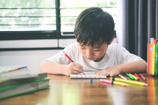 Niño de jardín de infantes dibujando y aprendiendo en casa. Educación, concepto de aprendizaje a distancia.