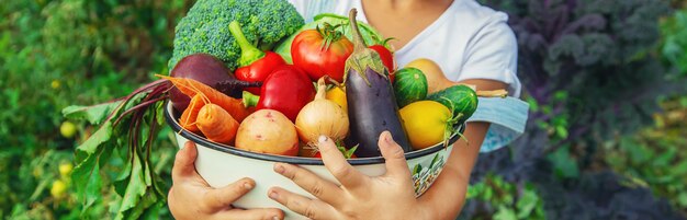 Niño en el jardín con verduras en sus manos