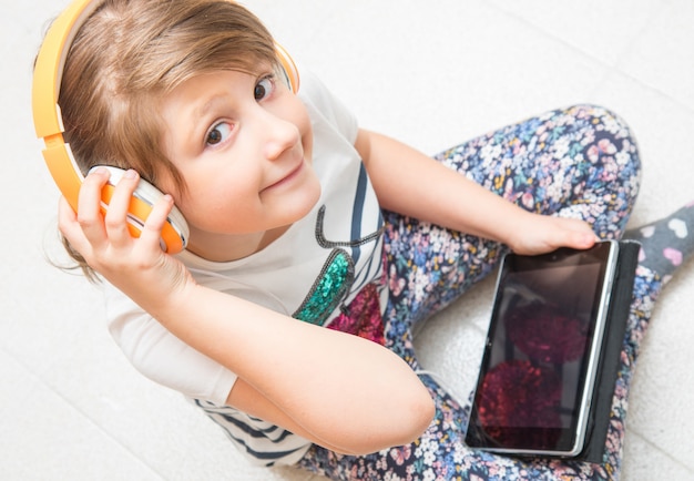 niño joven está escuchando música con auriculares en tableta