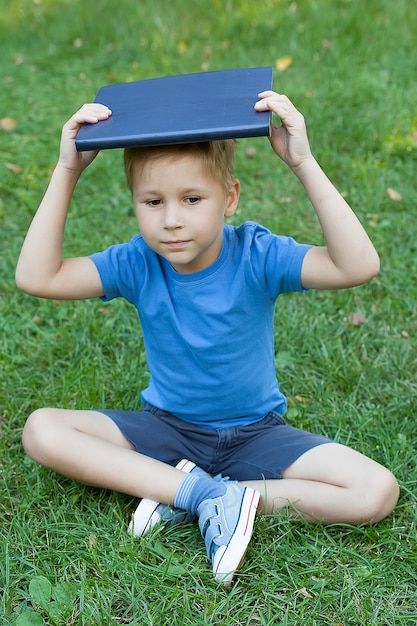 Niño joven, con, un, libro, en, el suyo, cabeza