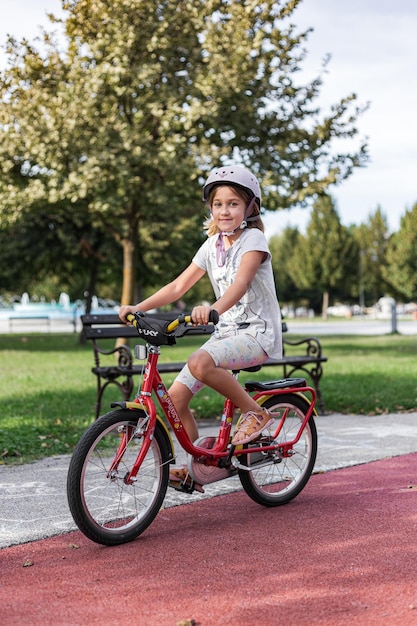 Un niño joven montando en su bicicleta en verano con un casco puesto