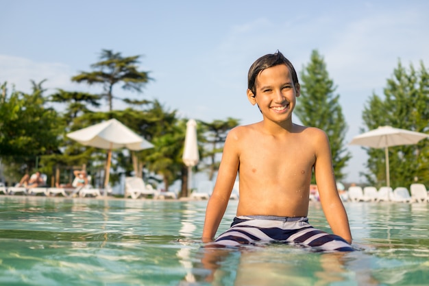 Niño joven niño niño splashing en la piscina que tiene diversión actividad de ocio