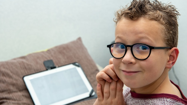 Foto un, niño joven, sonriente, utilizar, un, tableta