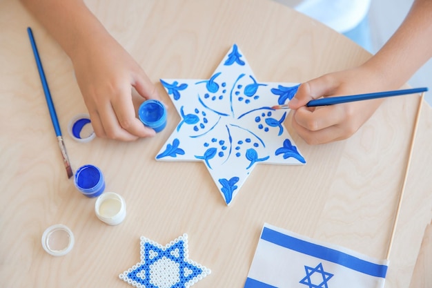 Foto niño judío pintando estrella en casa